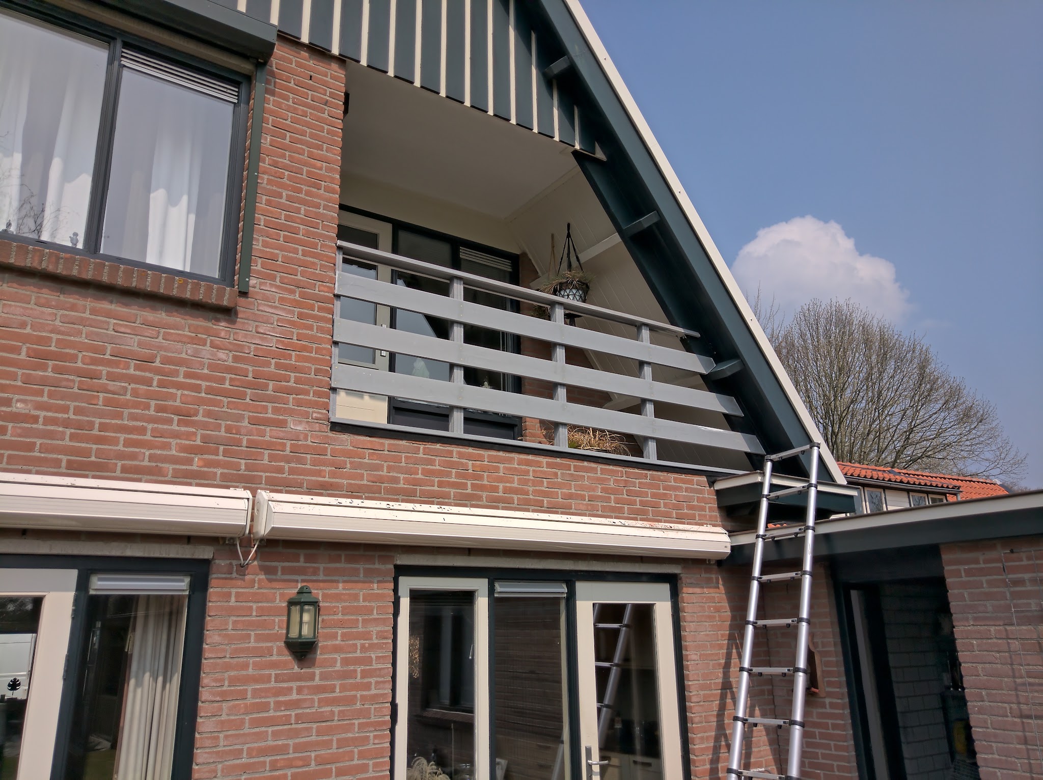 Achtergevel van een woning met de ladder van Kell tegen de gevel tijdens onderhoudswerk