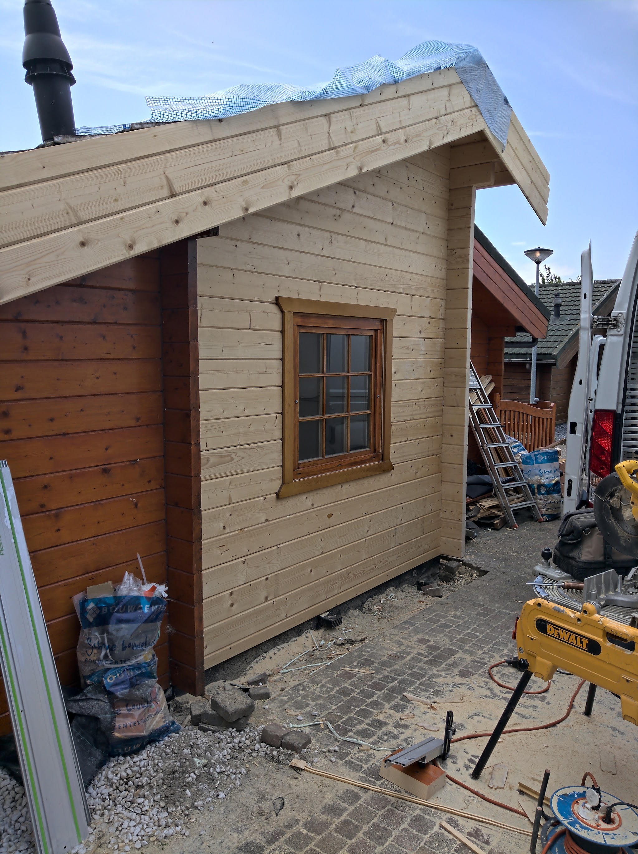 Houten tuinhuis in opbouw, met de wanden geplaatst en het dak nog open