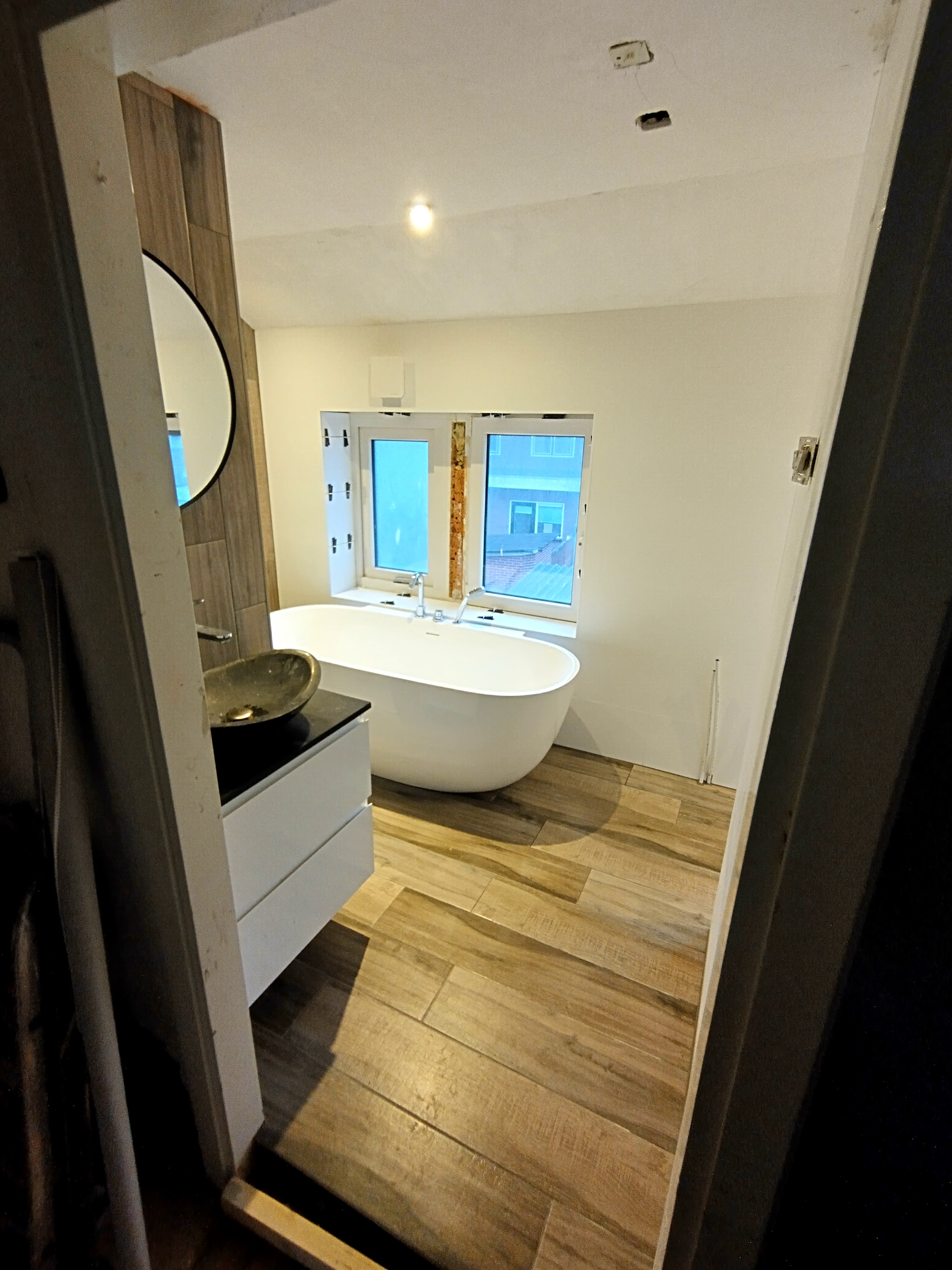 Door Kell gerenoveerde badkamer met vrijstaand bad, houtlook vloer en zwevend wastafelmeubel